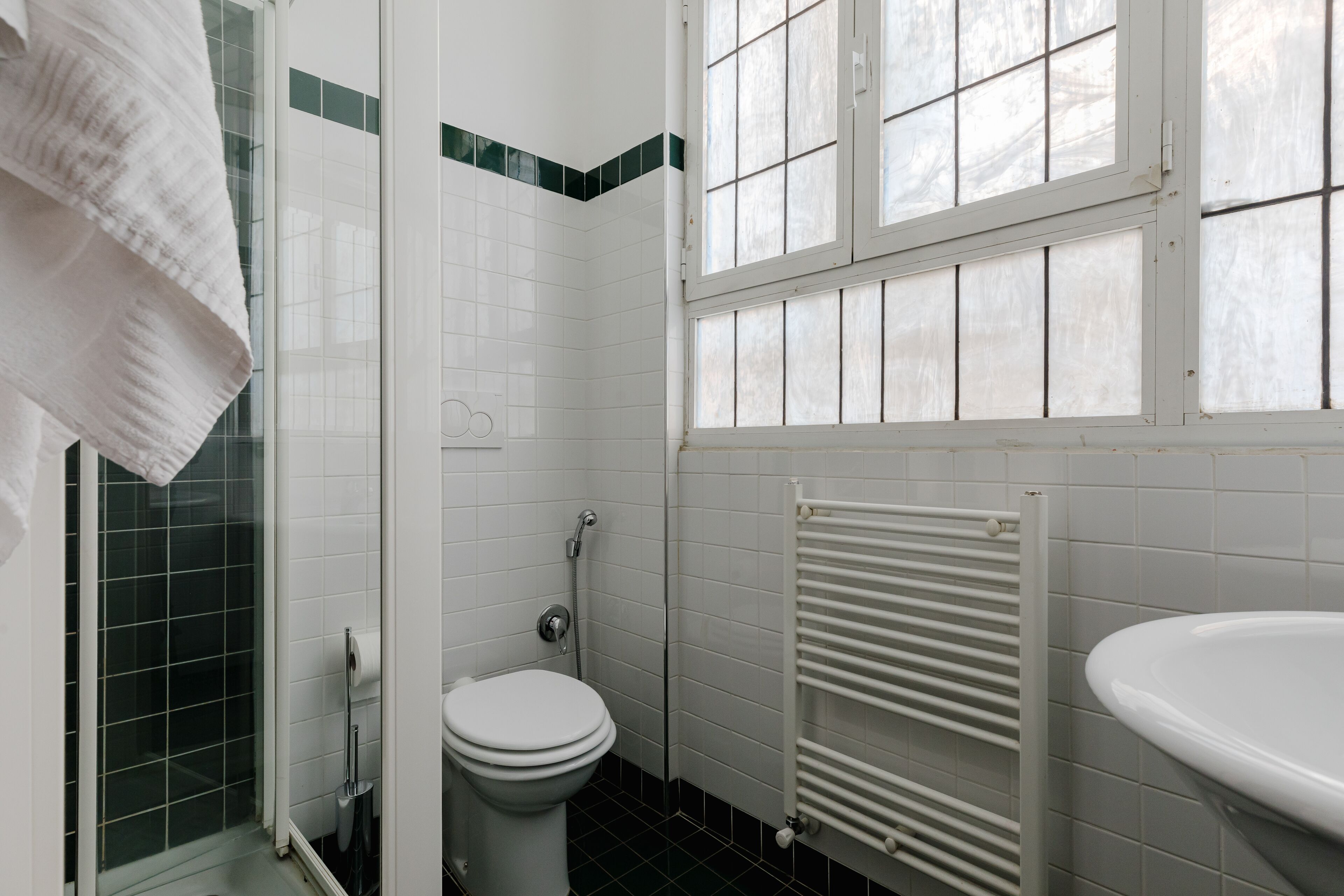 Une salle de bain comprenant des toilettes, une douche, un lavabo et une fenêtre.