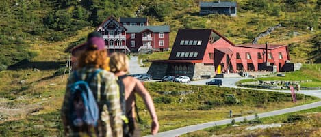 Un bâtiment rouge avec un toit en pente, entouré d’un paysage verdoyant, avec quelques autres bâtiments visibles au loin.