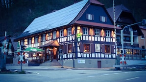 A traditional half-timbered building with a sign for a restaurant and a parking sign. - Landgasthof Rebstock (Ottenhofen im Schwarzwald)