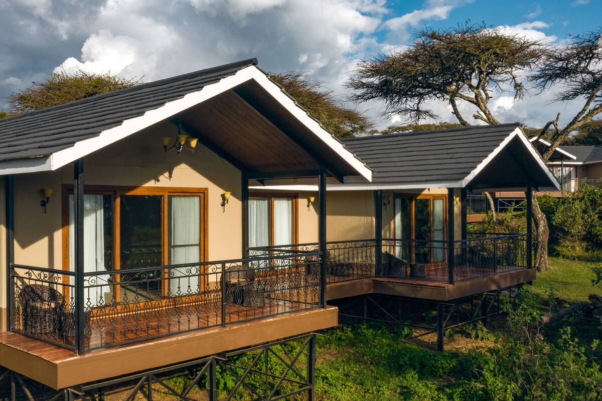 A bungalow with a balcony, a covered outdoor seating area, and a view of the surrounding landscape.