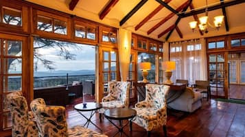 A spacious room with large windows, wooden flooring, and a variety of seating options including chairs and a sofa.