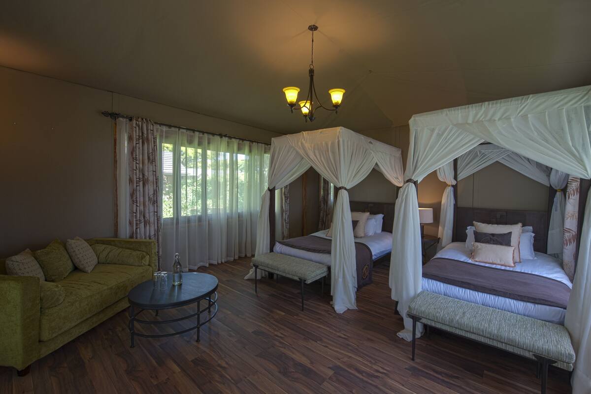 A room with a bed, a sofa, a round table, and a chandelier.