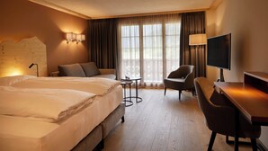 A hotel room with two beds, a desk, a chair, a TV, and a small table. - Hotel Alpenland (Lauenen)