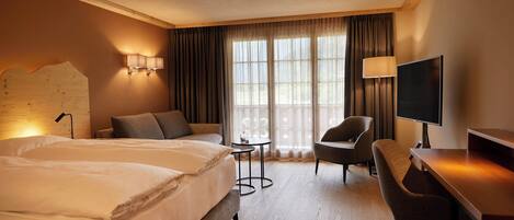 A hotel room with two beds, a desk, a chair, a TV, and a small table.