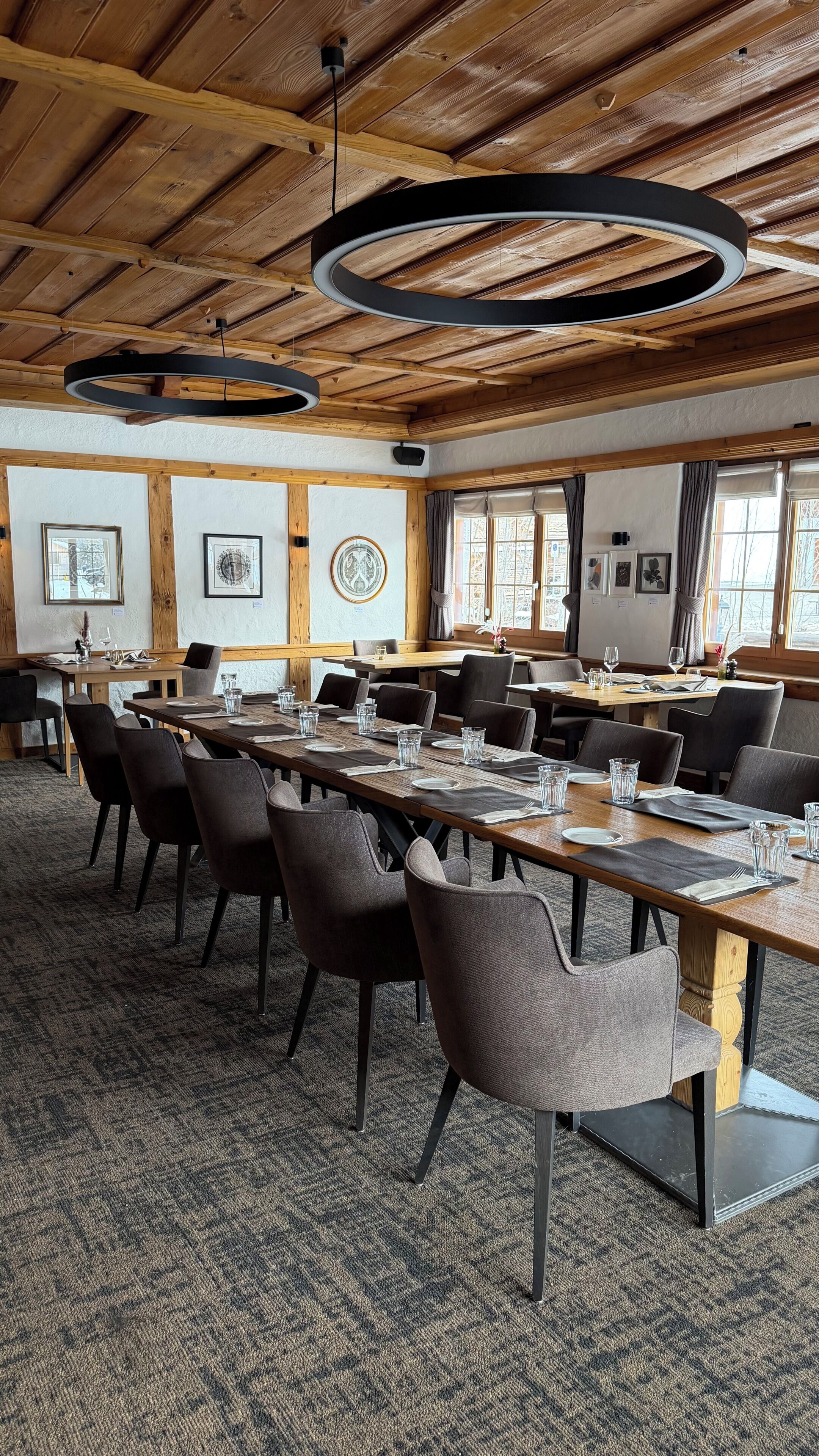 A conference room with long tables, chairs, and a wooden ceiling.