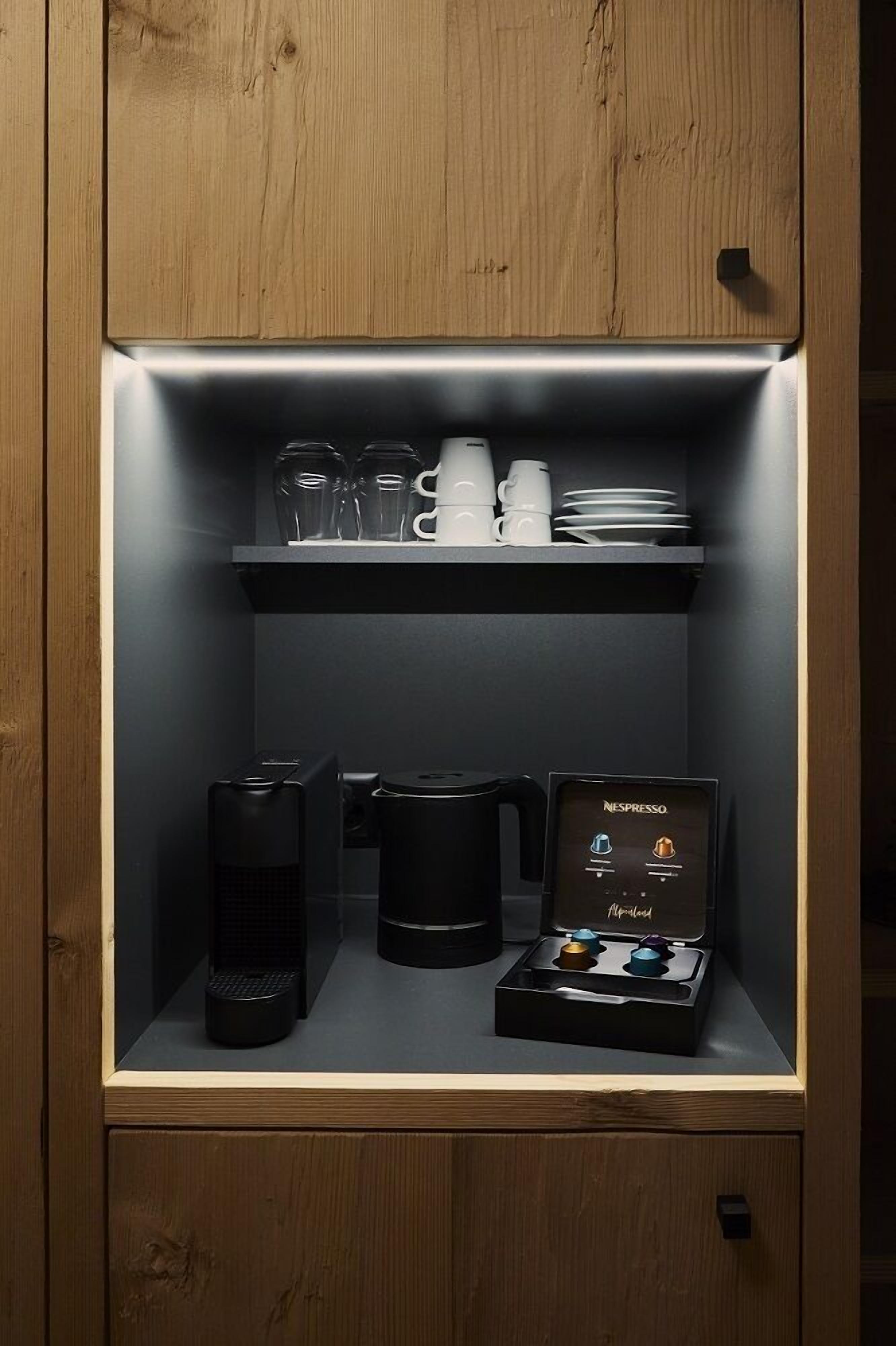 Un meuble de cuisine contenant une machine à café, des tasses et une machine Nespresso.