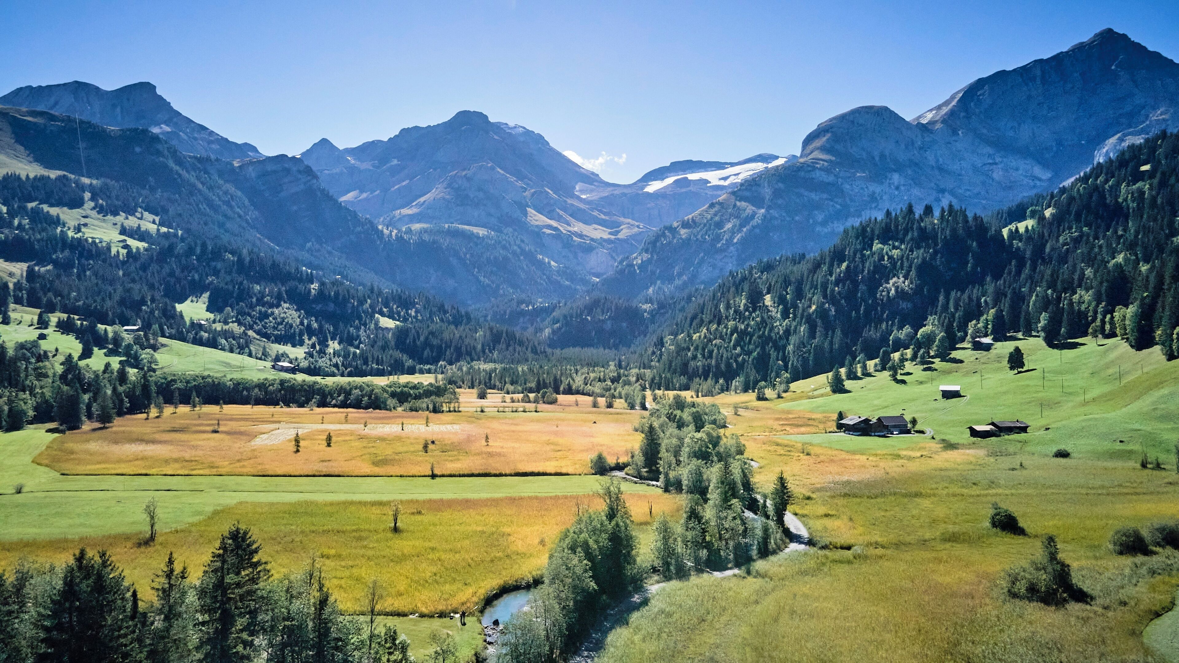 A mountainous landscape with a valley, fields, and scattered buildings.