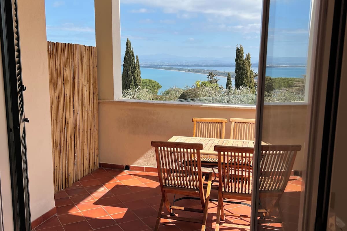 Ein Balkon mit Tisch und Stühlen, Blick auf das Meer und eine Bambus-Umzäunung.