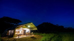 A tent with a canopy and a table set up outside at night.