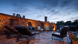 A stone building with a fireplace, outdoor seating, and a stone patio.