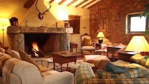 A cozy living room with a stone fireplace, wooden beams, and a comfortable seating area.