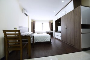 Ein Hotelzimmer mit Bett, Schreibtisch, Stuhl, Kleiderschrank und Fernseher.