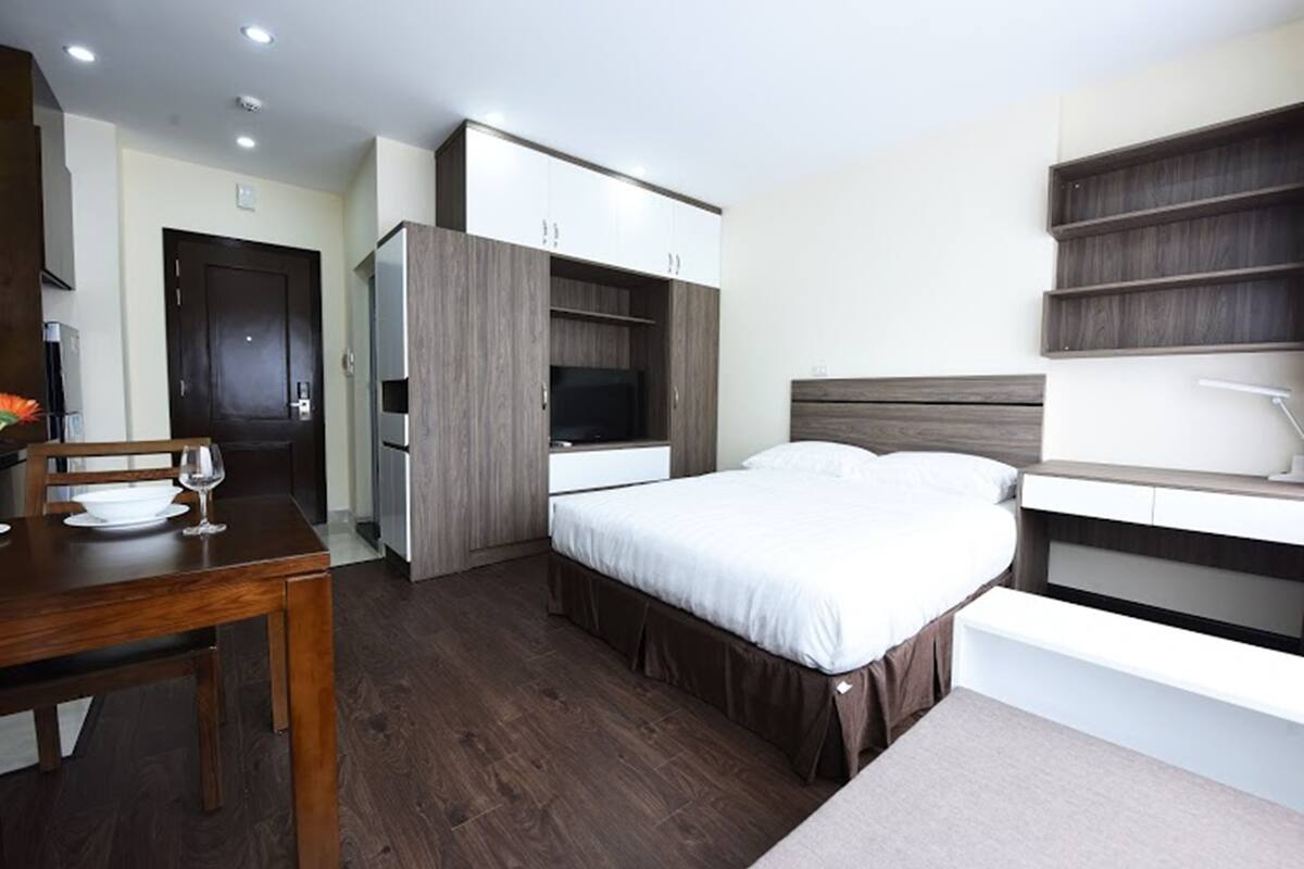 Ein modernes Schlafzimmer mit Bett, Schreibtisch mit Stuhl, Esstisch und integriertem Kleiderschrank.