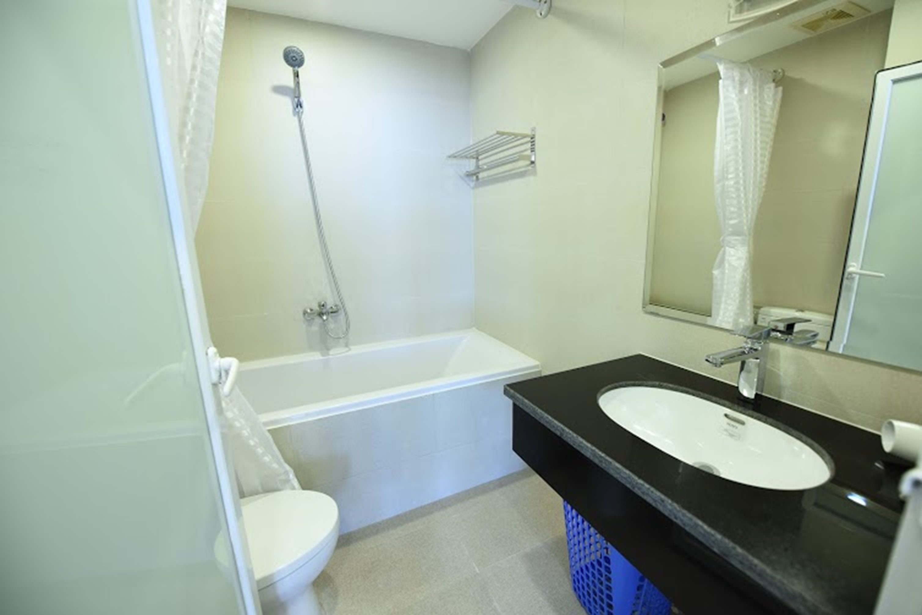 A bathroom with a white toilet, a bathtub, a sink with a black countertop, and a shower with a curtain.