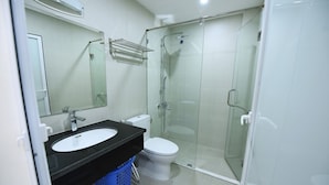 A modern bathroom with a glass-enclosed shower, a white toilet, and a black sink. - Granda Legend Apartment (Hanoi)
