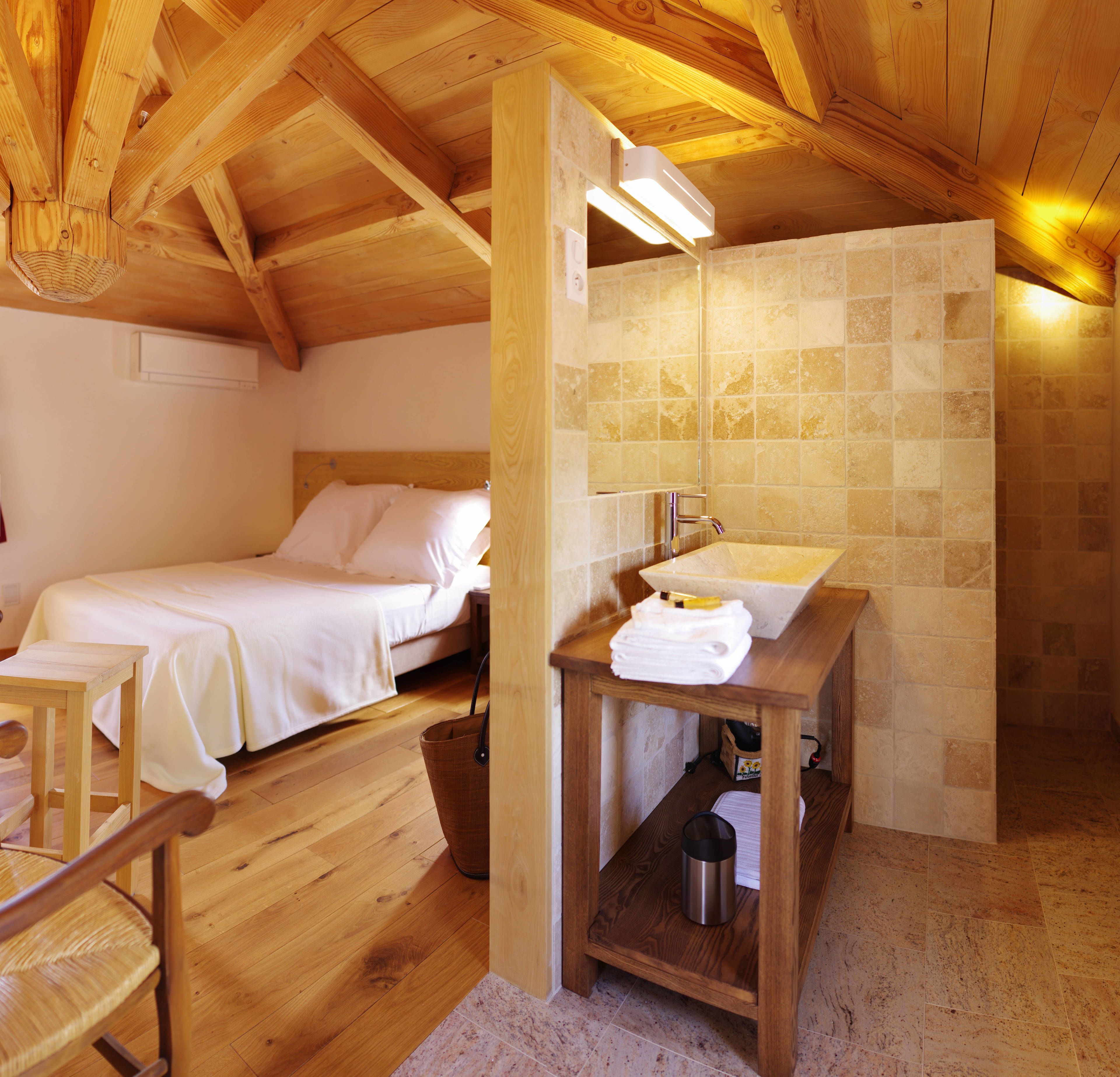Una habitación de madera con una cama, una mesa de madera con un lavabo y una pared de azulejos.