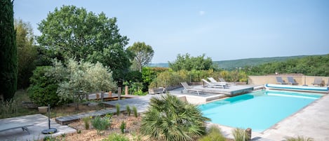 Una piscina al aire libre, sombrillas, sillones reclinables de piscina