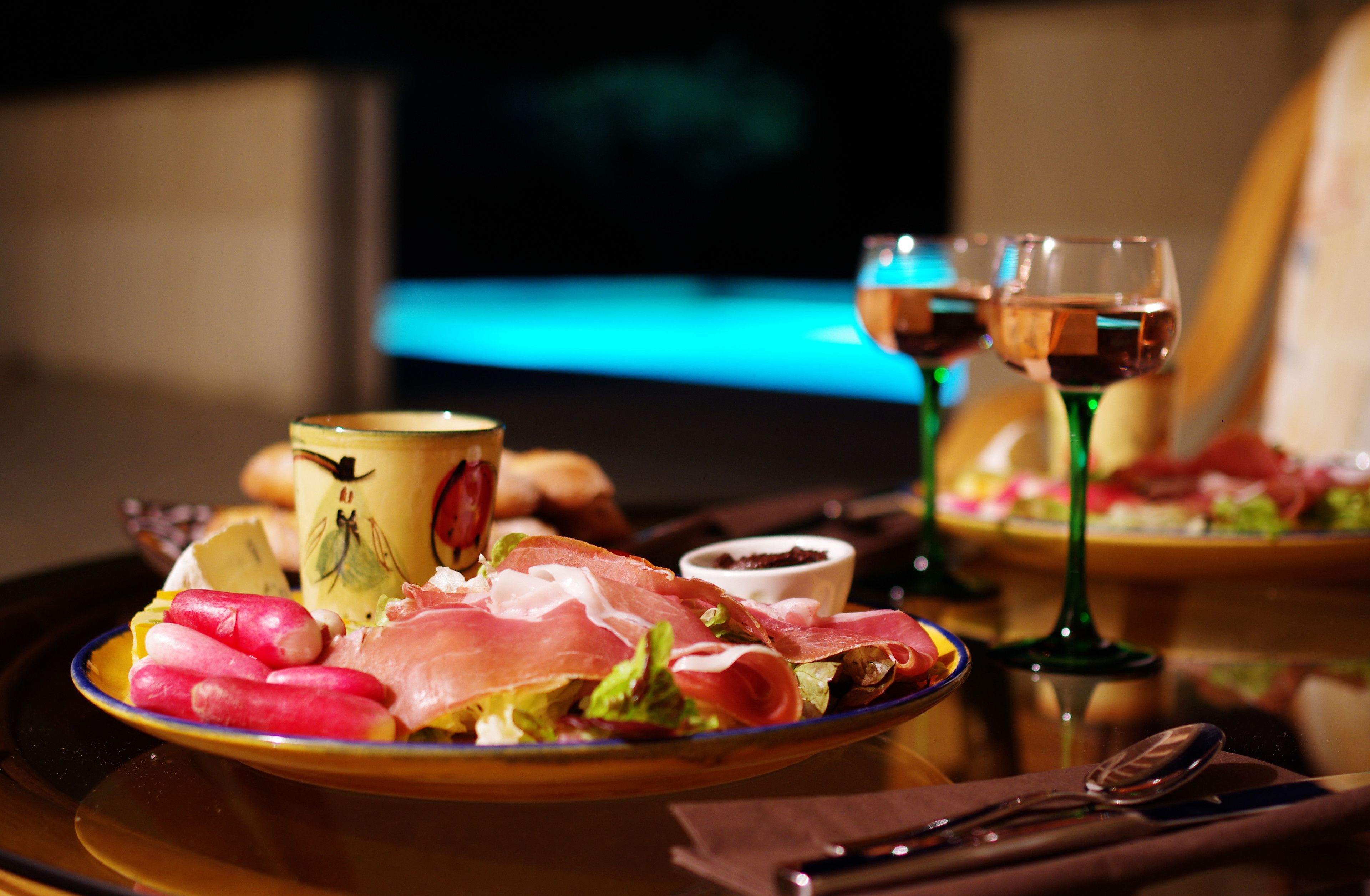 Een eettafel met een bord eten, een kop en twee wijnglazen.