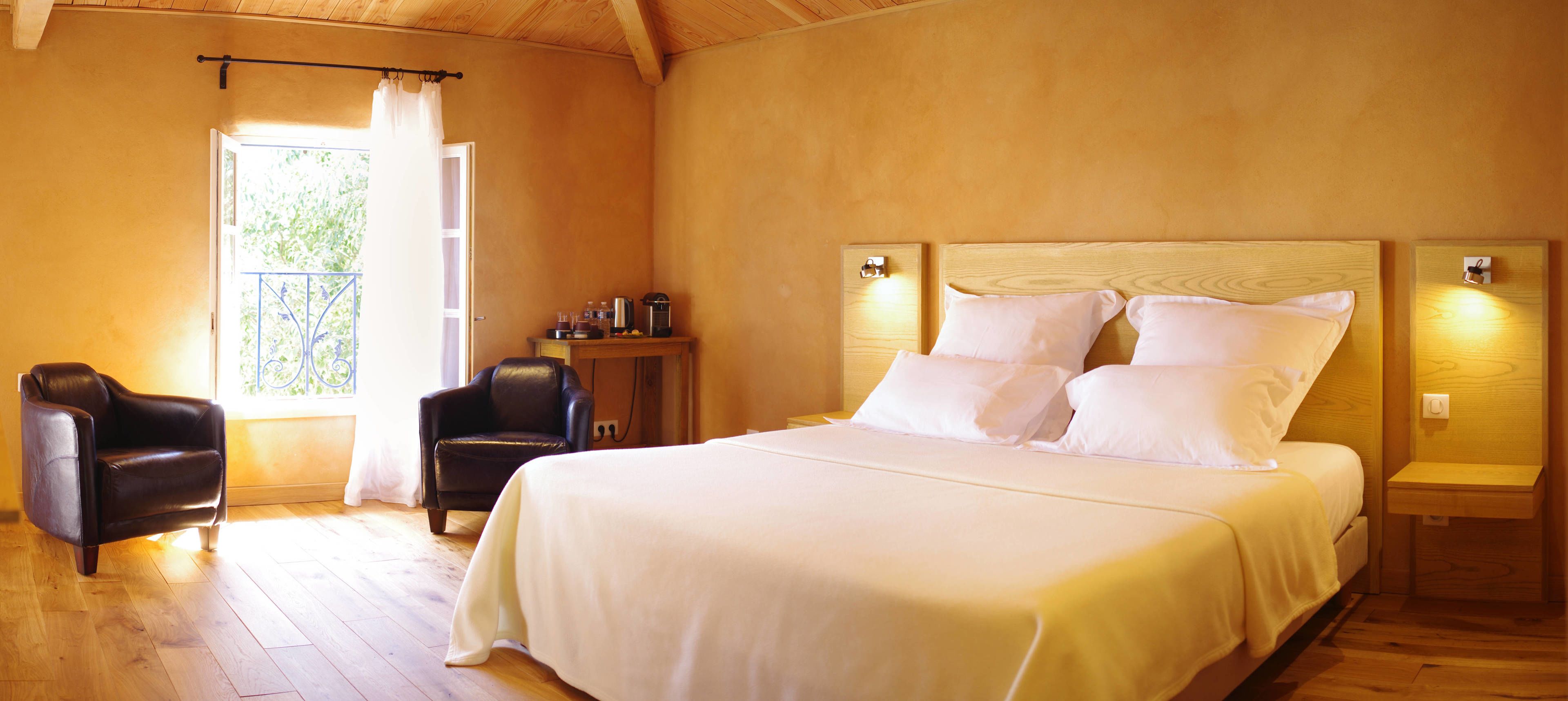 Een slaapkamer met een groot bed, twee nachtkastjes, een stoel en een tafeltje met een koffiezetapparaat.