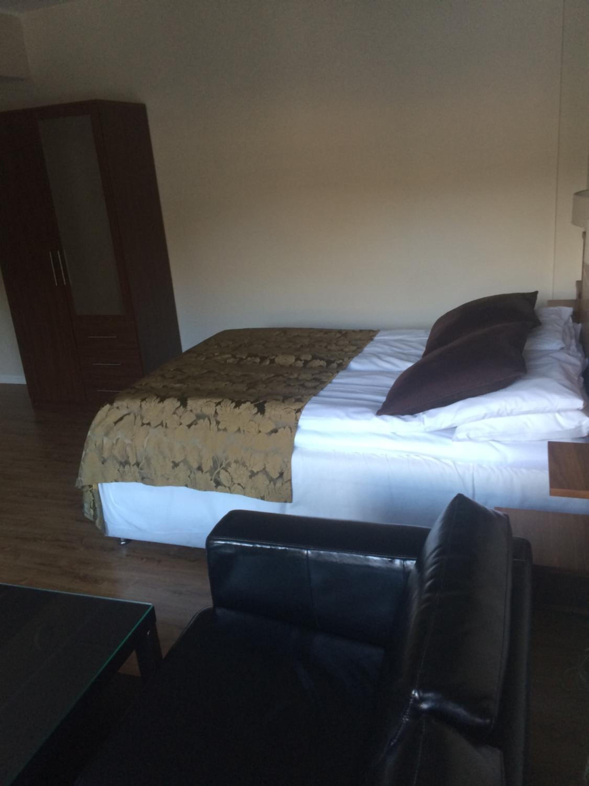 A bedroom with a bed, a wardrobe, and a small table.