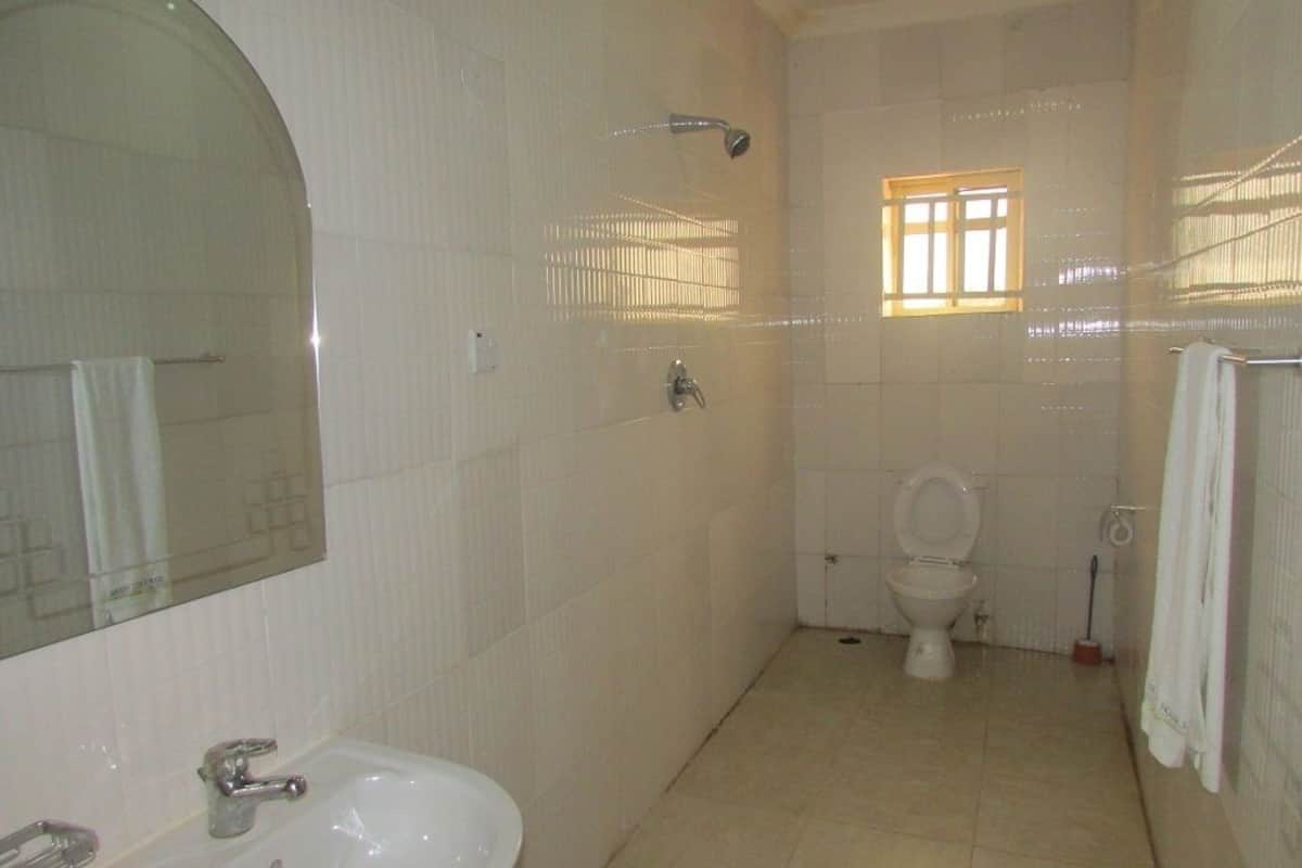 Ein Badezimmer mit Waschbecken, Toilette, Dusche und einem Fenster mit Gitterstäben.