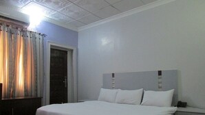 Un dormitorio con cama, mesita de noche, escritorio y puerta.