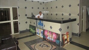 Una recepción con mostrador, zona de estar con sillón y pared con diseño.