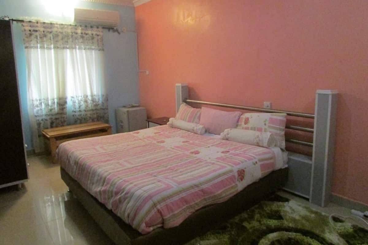 Ein Schlafzimmer mit Bett, Nachttisch, Bank und Kleiderschrank.