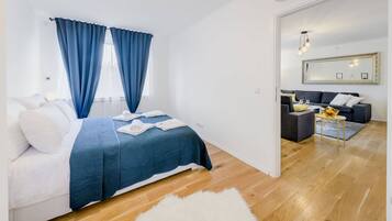 Een moderne slaapkamer met een groot bed, blauwe gordijnen en een houten vloer.