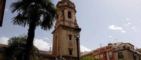 A historic building with a clock tower, surrounded by palm trees and modern buildings.