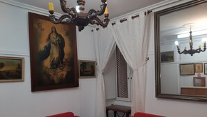 A room with two red sofas, a large mirror, a chandelier, and framed artwork on the walls. - Pensión Martín (Jaén)