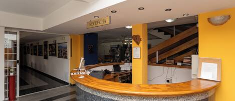 A reception area with a curved granite counter, a sign reading 'RECEPTION,' and a staircase in the background.
