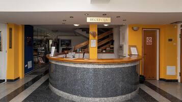 A reception area with a counter, a sign reading 'RECEPCJA,' and a staircase in the background.