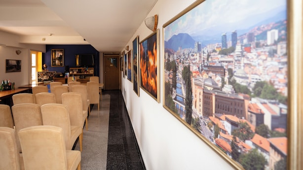 A hotel corridor with framed cityscape pictures, a bar area, and seating.