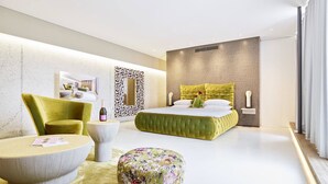 A modern bedroom with a green bed, a yellow armchair, a round ottoman, and a white round table. - Das Spritzenhaus (Eltville am Rhein)