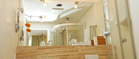Une salle de bain moderne avec un meuble-lavabo en marbre, une cabine de douche en verre et un porte-serviettes apparent.