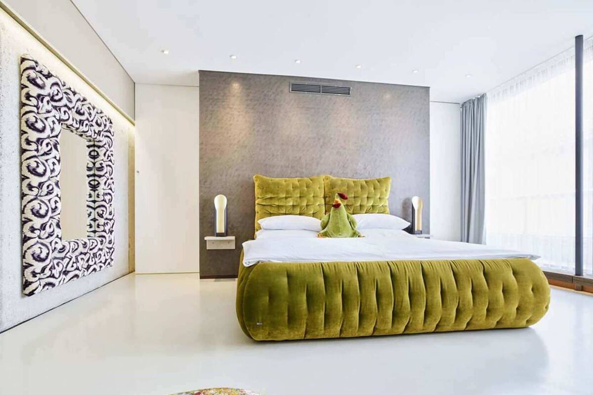 A modern bedroom with a large bed, a decorative wall piece, and a window with curtains.