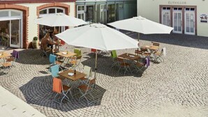 An outdoor patio area with tables and chairs, umbrellas, and potted plants. - Das Spritzenhaus (Eltville am Rhein)