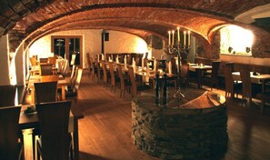 A restaurant with stone arches, wooden tables, and chairs.