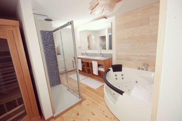A modern bathroom with a glass shower enclosure, a freestanding bathtub, and a vanity with two sinks.