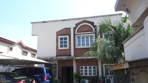 A two-story building with a flat roof, a garage, and a covered parking area. - House No 12B (Lagos)