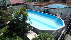 A swimming pool surrounded by greenery, with a view of buildings in the background. - House No 12B (Lagos)