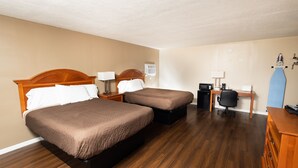 Habitació d'hotel amb dos llits, escriptori, cadira, màquina de cafè i una taula petita amb una làmpada.