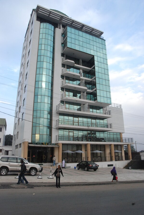 A multi-story building with a glass facade, a central entrance with a canopy, and a staircase leading to the upper floors. - Churchill Hotel (Addis Ababa)