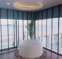 Un baño moderno con una bañera grande, una planta en maceta y vistas al agua.