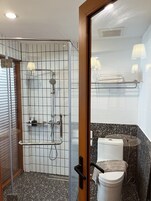 Un baño con ducha compartimentada con vidrio, inodoro y lavamanos.