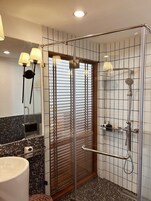 Un baño moderno con cabina de ducha de vidrio, tocador con lavabo y espejo.