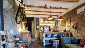 A cozy living room with a red vintage stove, a green sofa, and a wooden floor. -  Assos Sunset Boutique Hotel (Ayvacik)