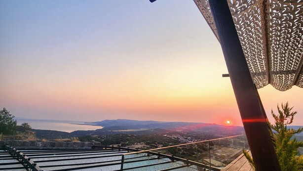 A wooden deck with a metal railing, overlooking a scenic landscape with a sunset. -  Assos Sunset Boutique Hotel (Ayvacik)