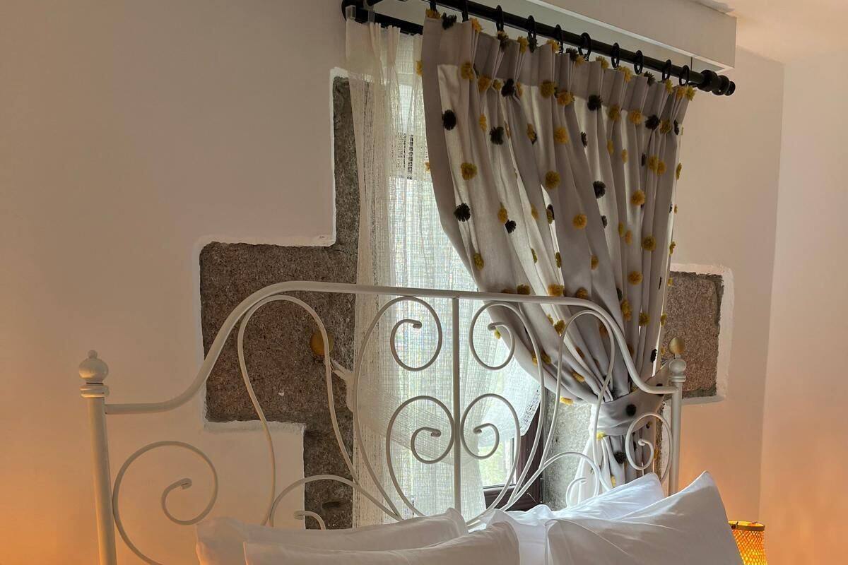 A bed with white bedding, a crocheted blanket, and a metal headboard.